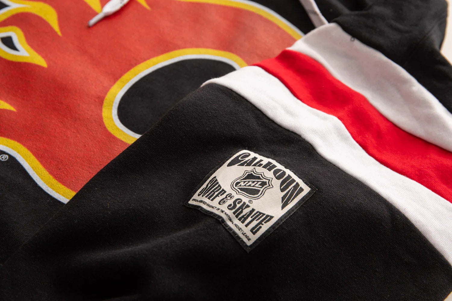 Calgary Flames varsity hoodie detail with red, yellow logo and Calhoun NHL patch