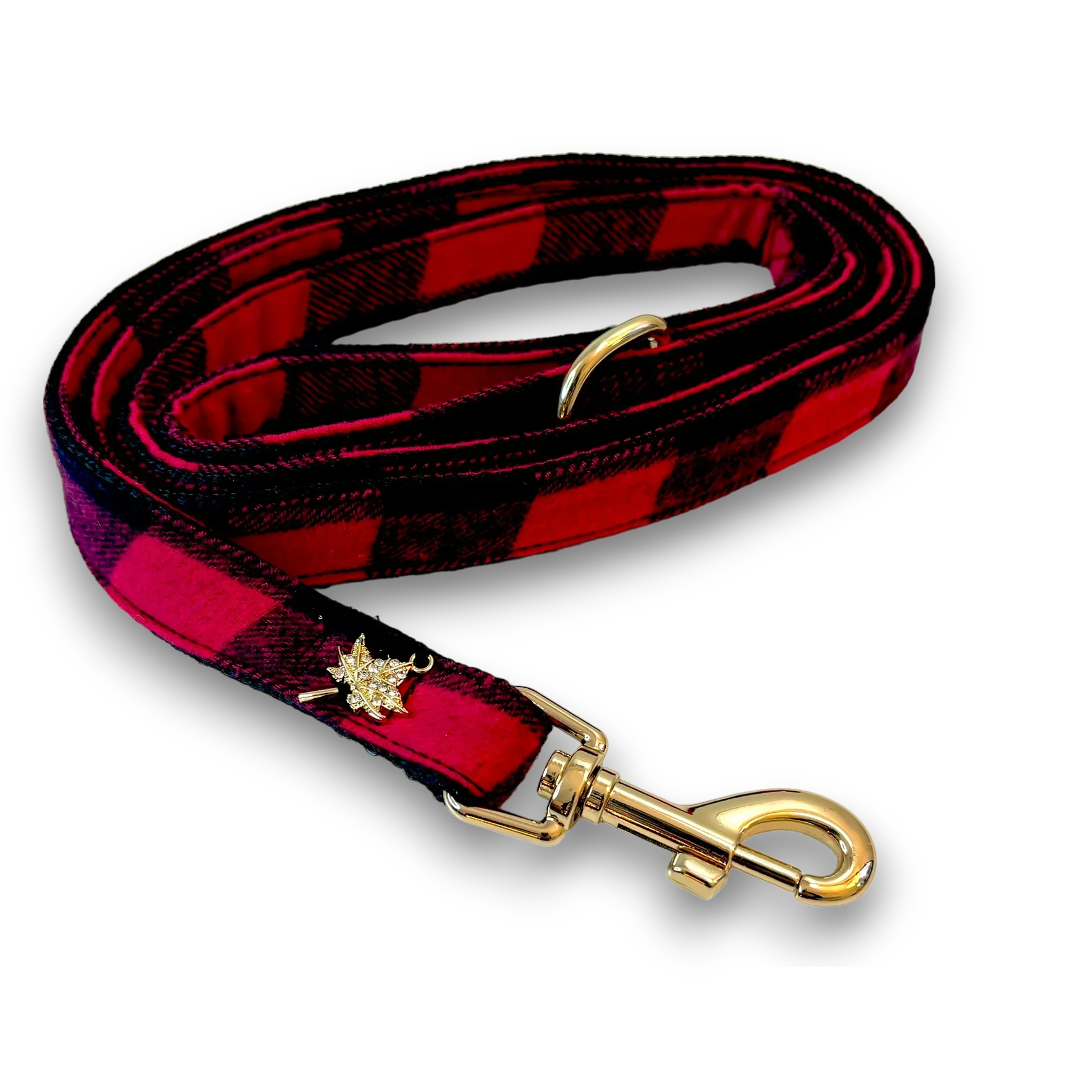 Red plaid dog leash with gold hardware and maple leaf charm on black background
