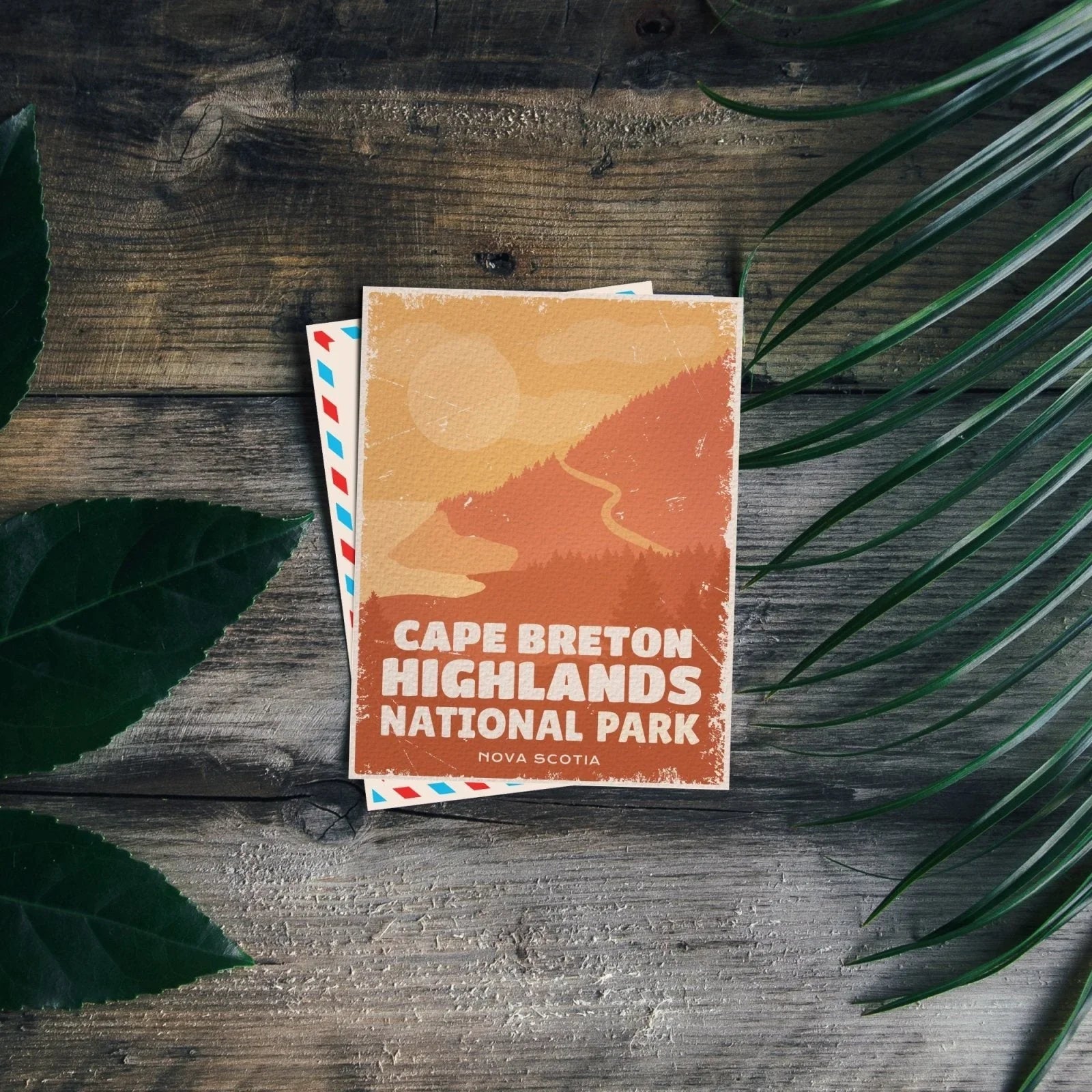 Cape Breton Highlands National Park postcard on rustic wood with green leaves, Nova Scotia.