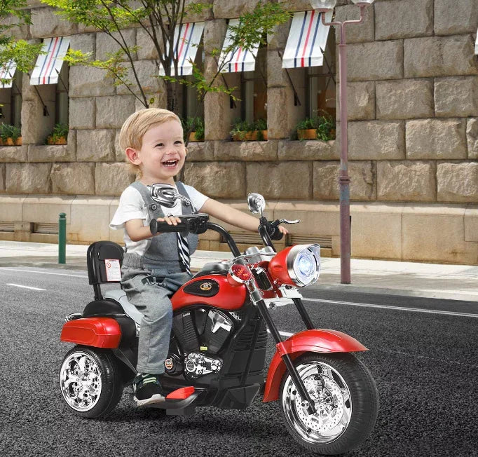 Smiling boy riding a red kids electric motorcycle on a city street