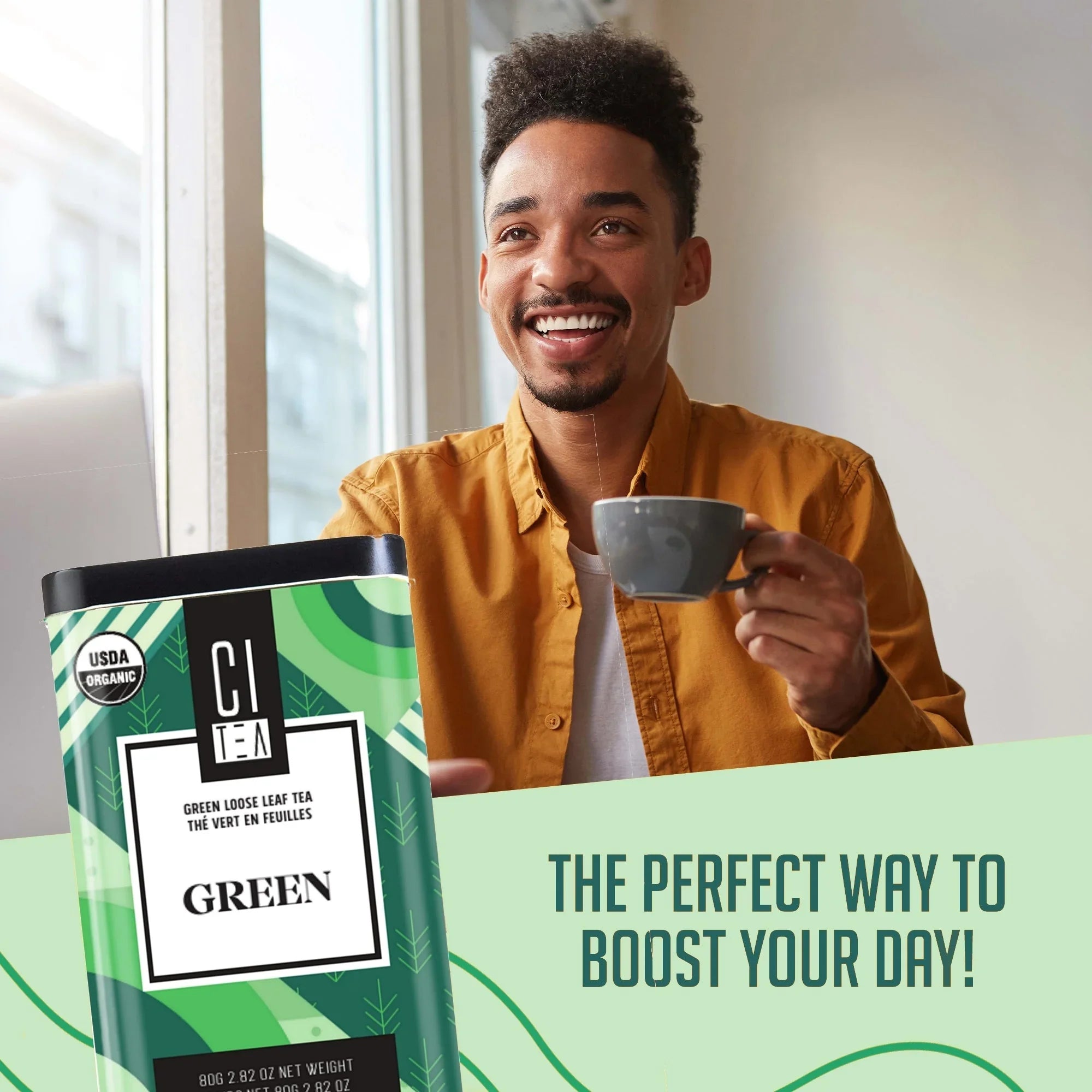 Smiling man enjoying cup of organic CI Tea green loose leaf tea by window, product package visible