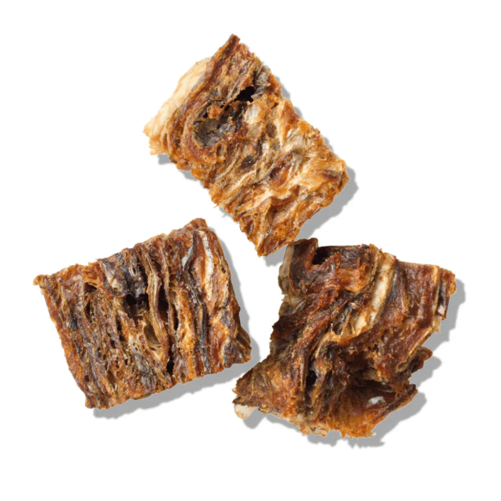 Three dehydrated cod skin cubes on white background, natural dog treats