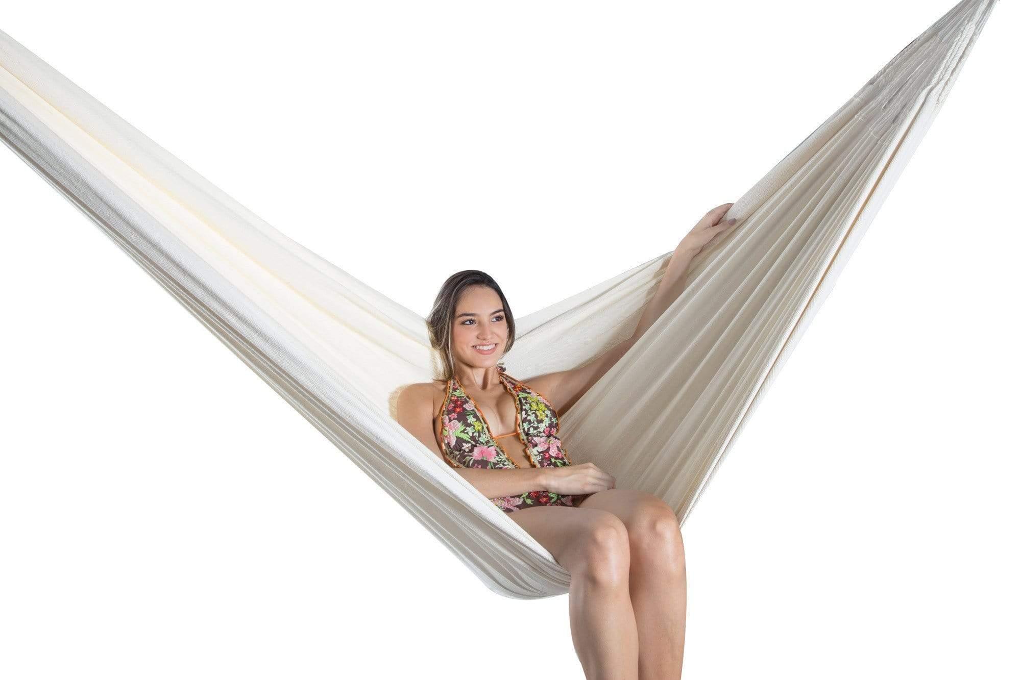Woman relaxing in a natural cotton hammock against a white background