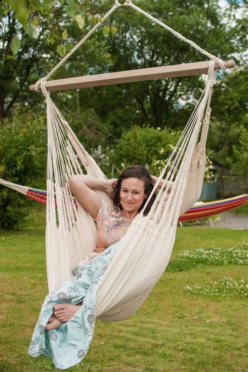 Woman relaxing in a Colombian hammock chair ecru outdoors, garden background