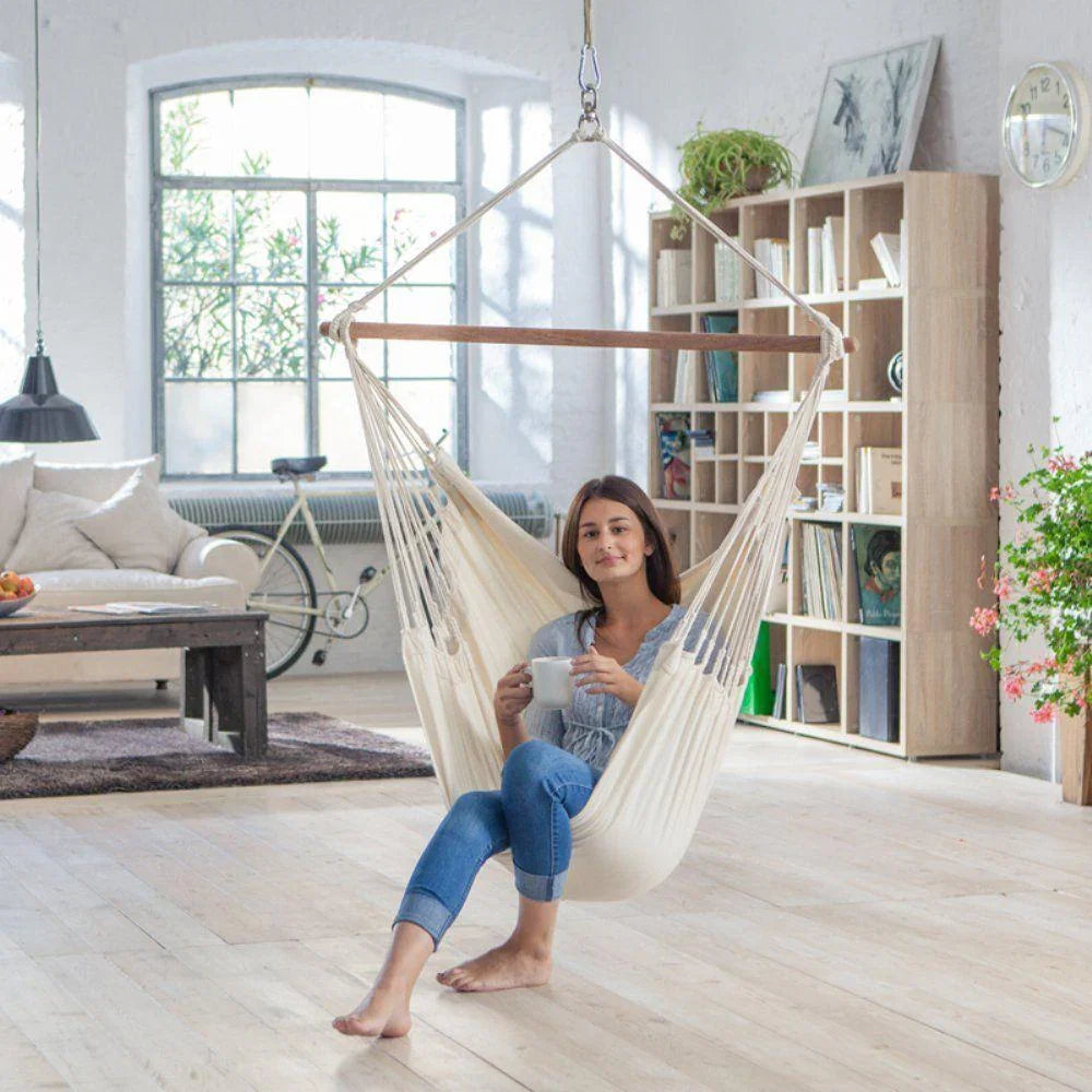 Woman relaxing in a Colombian ecru hanging chair with a mug in a bright modern living room