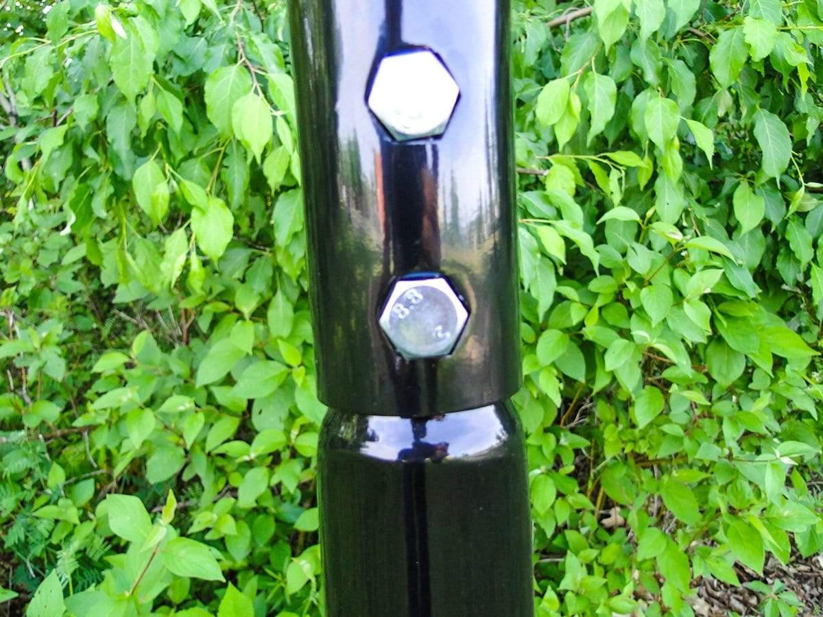 Close-up of black metal hammock chair stand with bolts, outdoor green leafy background