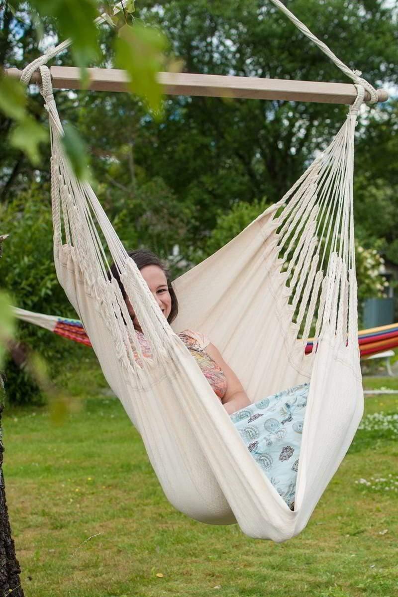 Woman relaxing in an ecru Colombian hammock chair outdoors on green grass