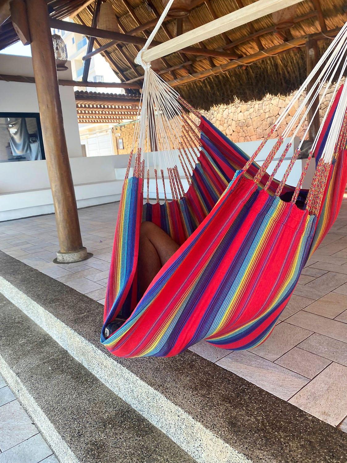 Colorful striped hammock chair under palapa roof on tiled patio