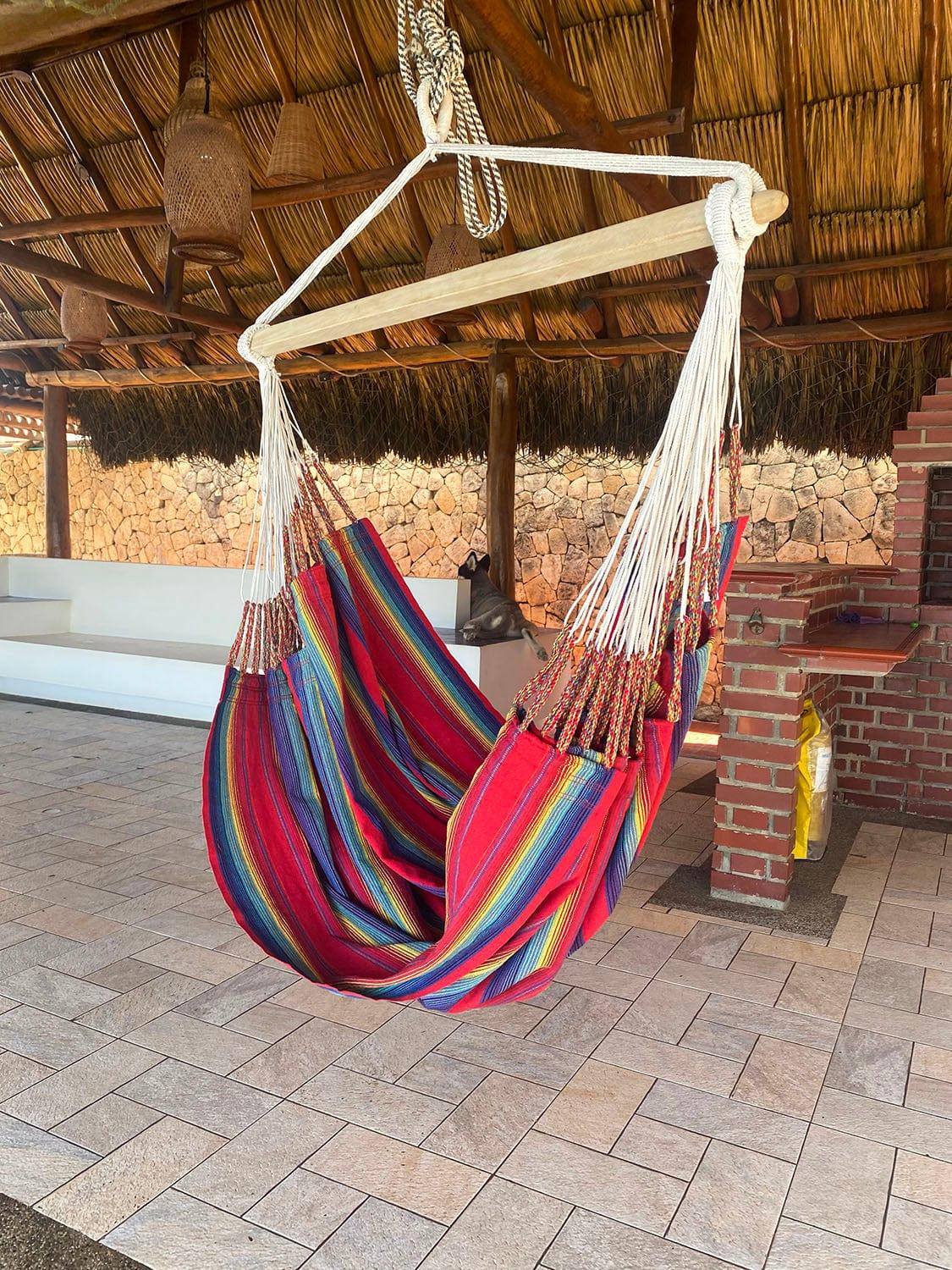 Colorful hammock chair under a thatched roof patio with stone walls and brick pillars