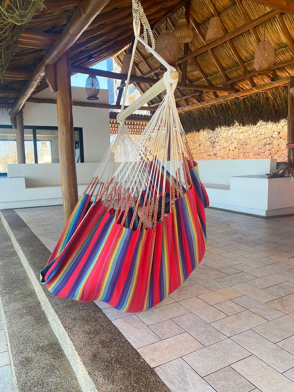 Colorful striped hammock chair hanging in a rustic, covered outdoor patio area