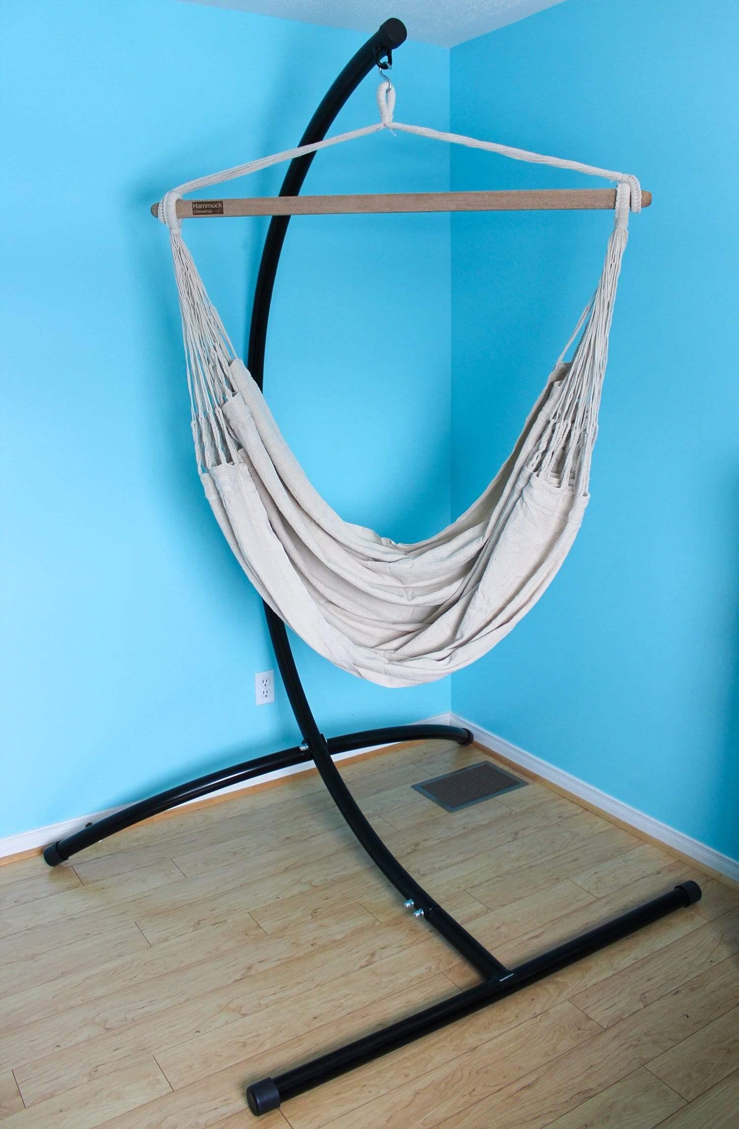 White Colombian hammock chair with black stand in a blue room on wooden floor