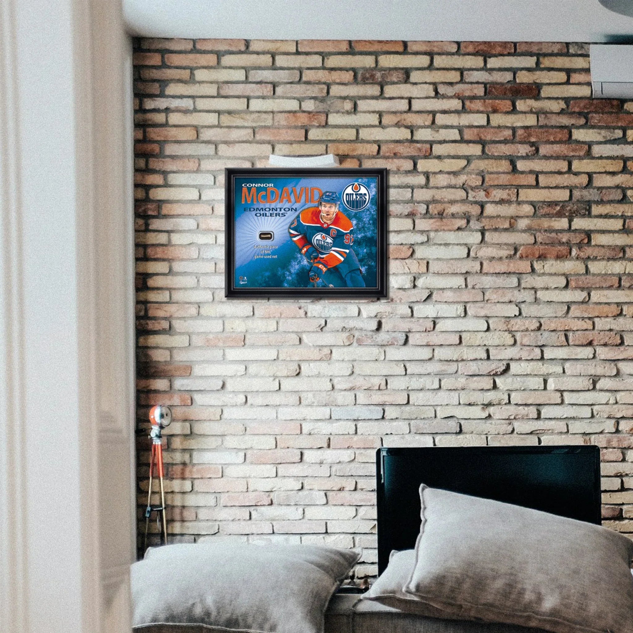 Framed Connor McDavid Edmonton Oilers hockey poster on brick wall above bed