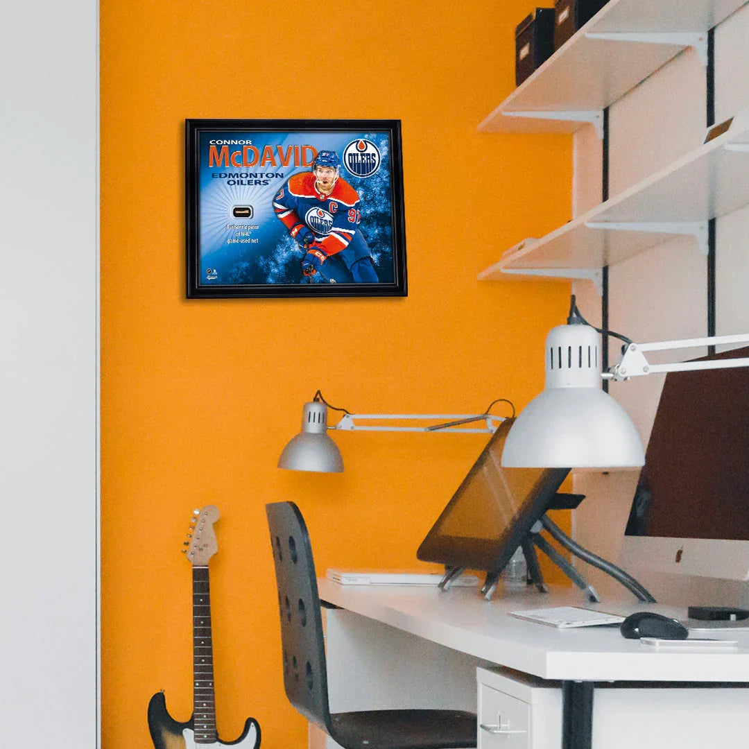 Framed Connor McDavid Edmonton Oilers hockey poster on orange wall in modern office