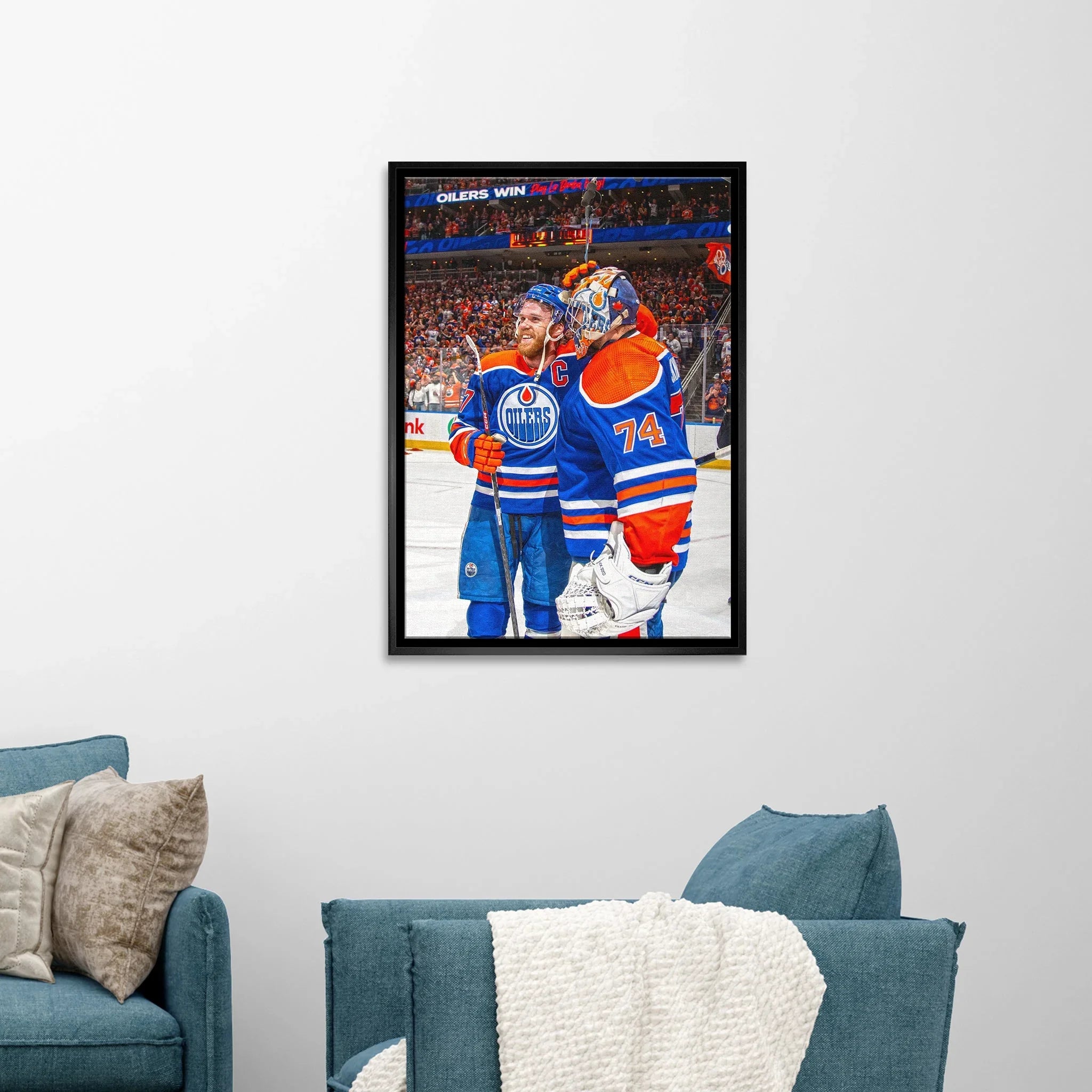 Framed Edmonton Oilers hockey artwork on white wall above blue sofa in modern living room