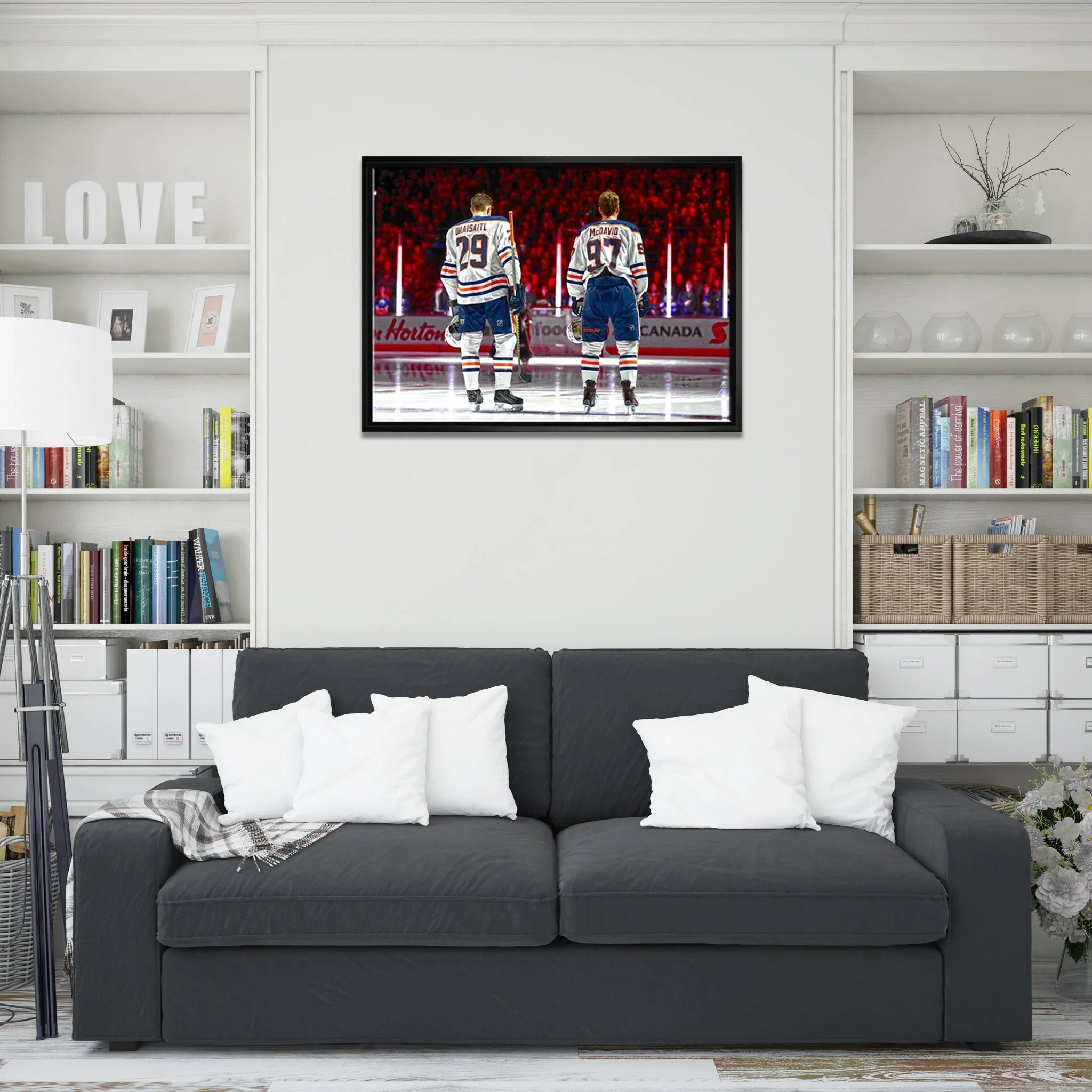 Modern living room with dark gray sofa, white pillows, and hockey player art on wall