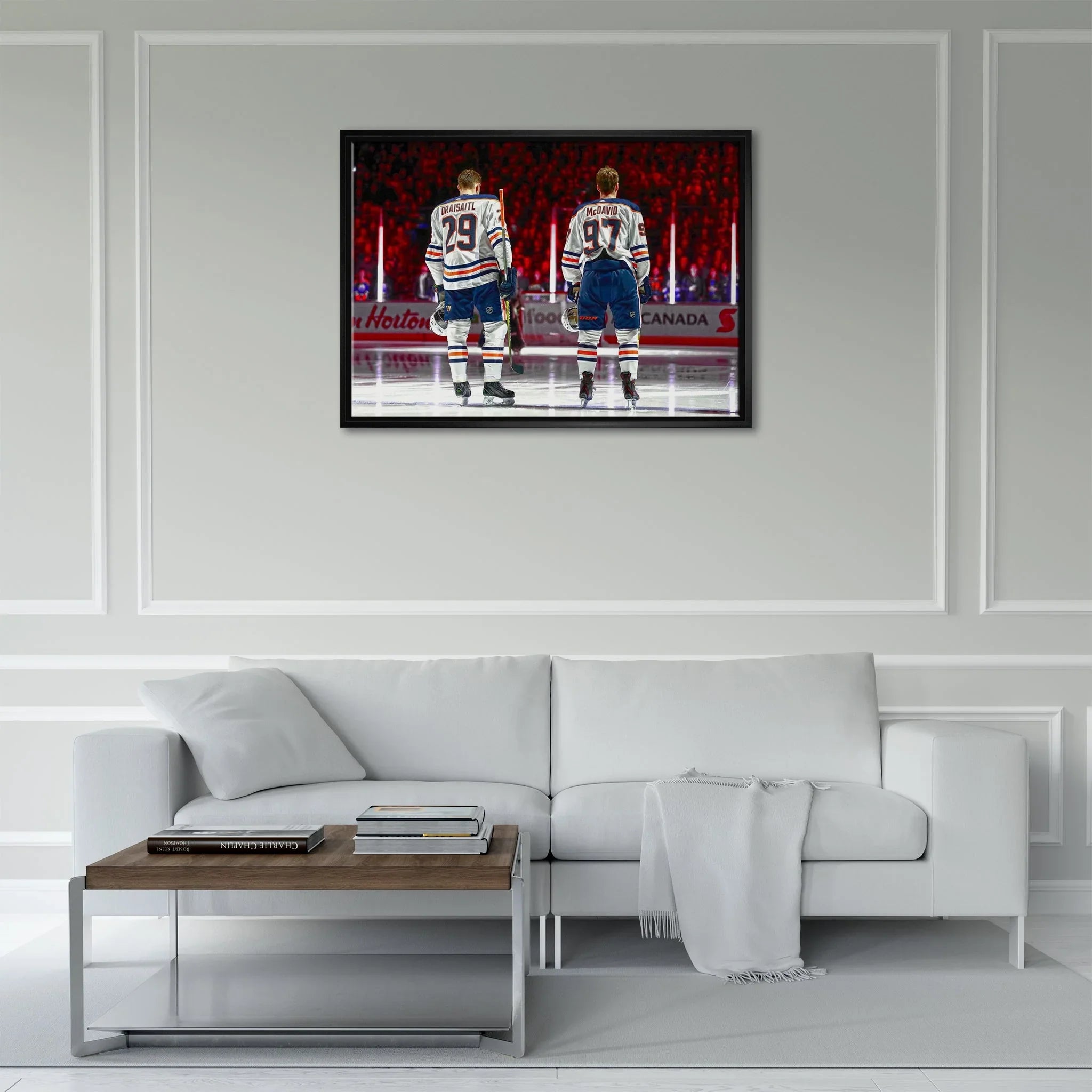 Framed hockey art of two players in uniforms on white wall above modern white sofa