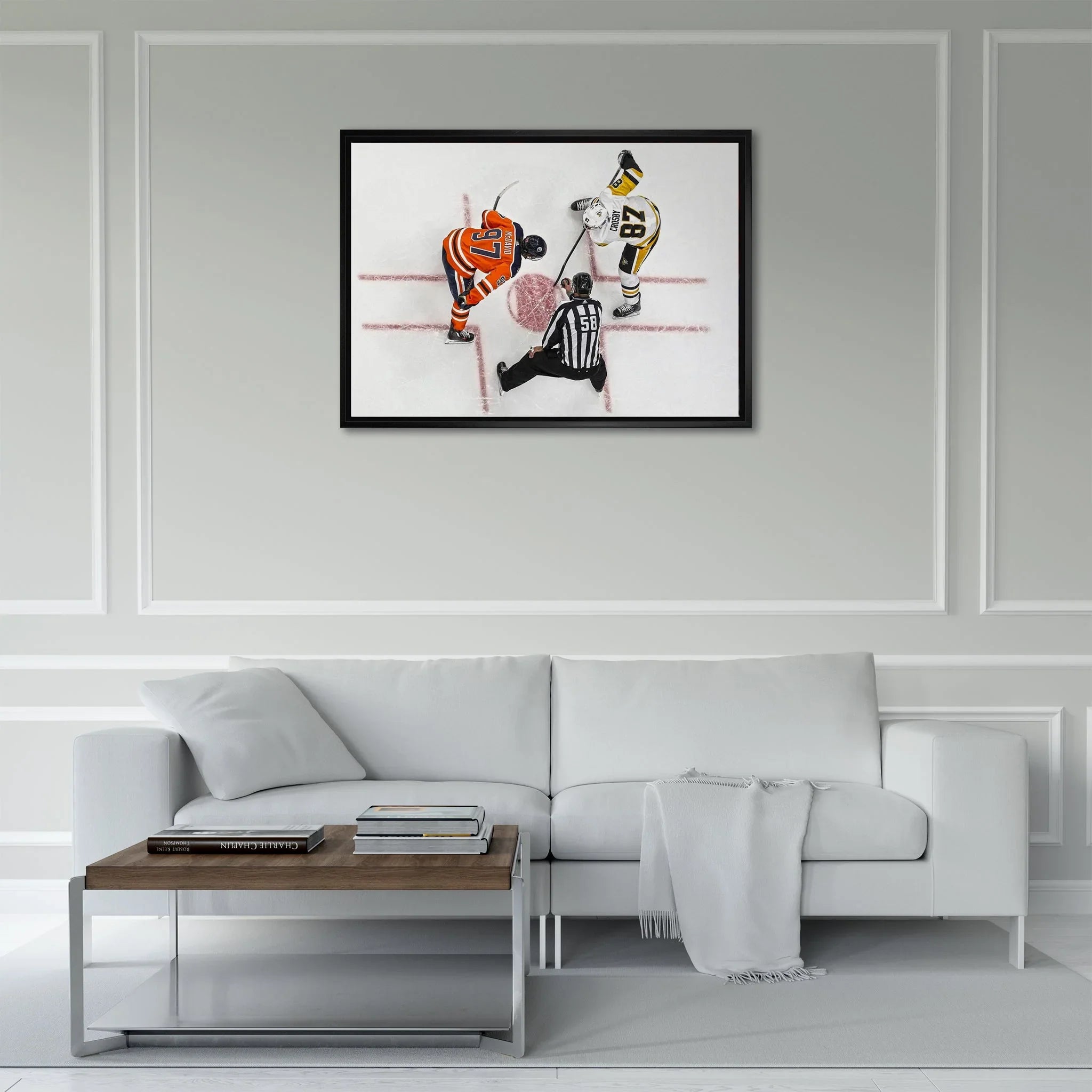 Modern living room with white sofa, wall art of hockey faceoff above, coffee table with books