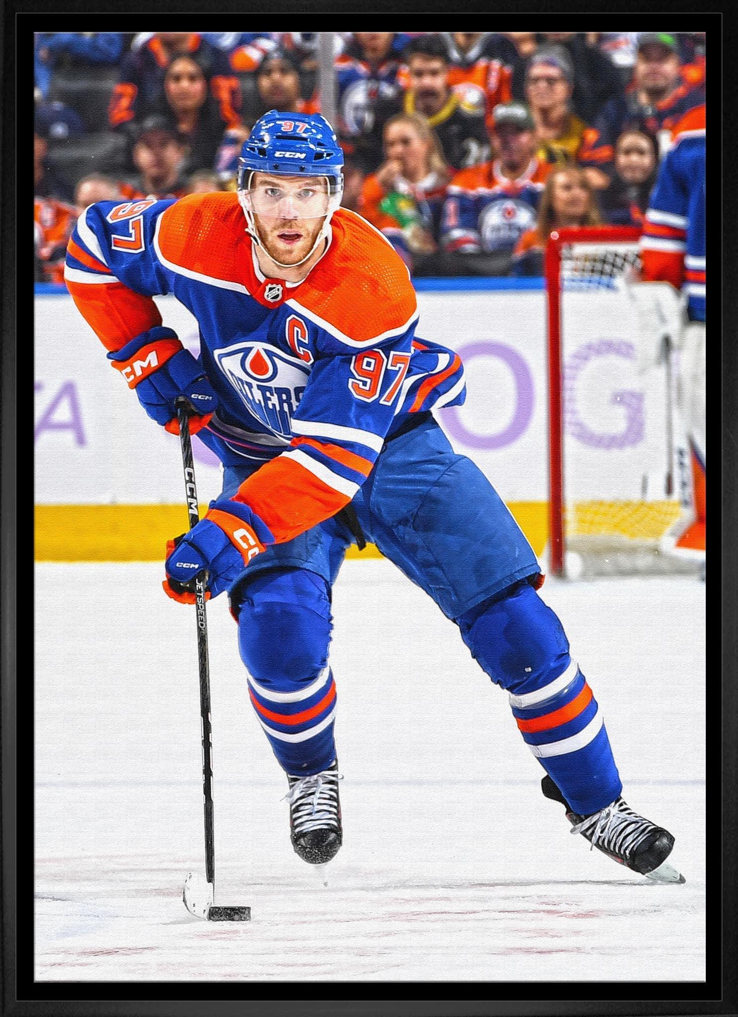Edmonton Oilers hockey player in blue and orange jersey skating on ice during game