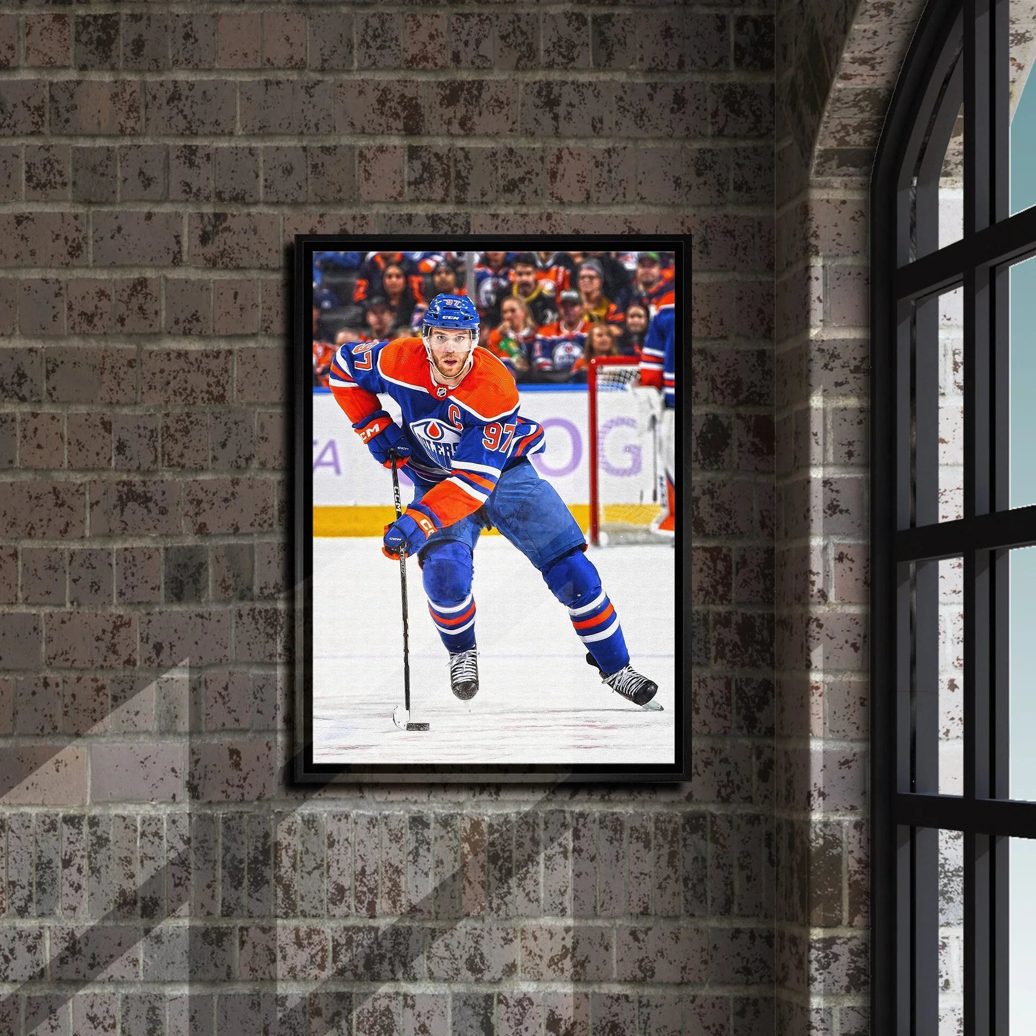 Framed photo of ice hockey player in blue and orange jersey displayed on brick wall