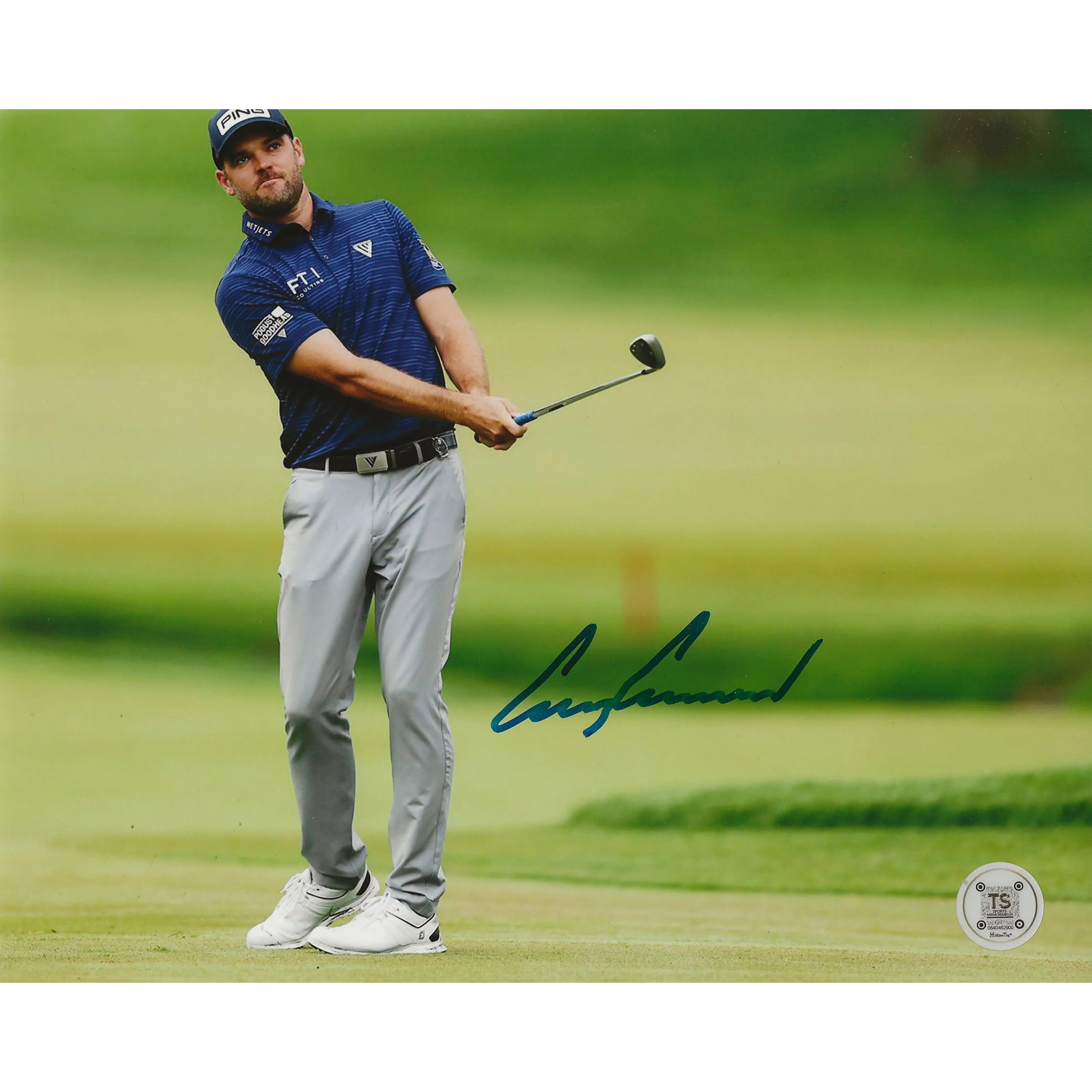 Golfer in blue shirt and gray pants swinging club on green golf course, autograph visible