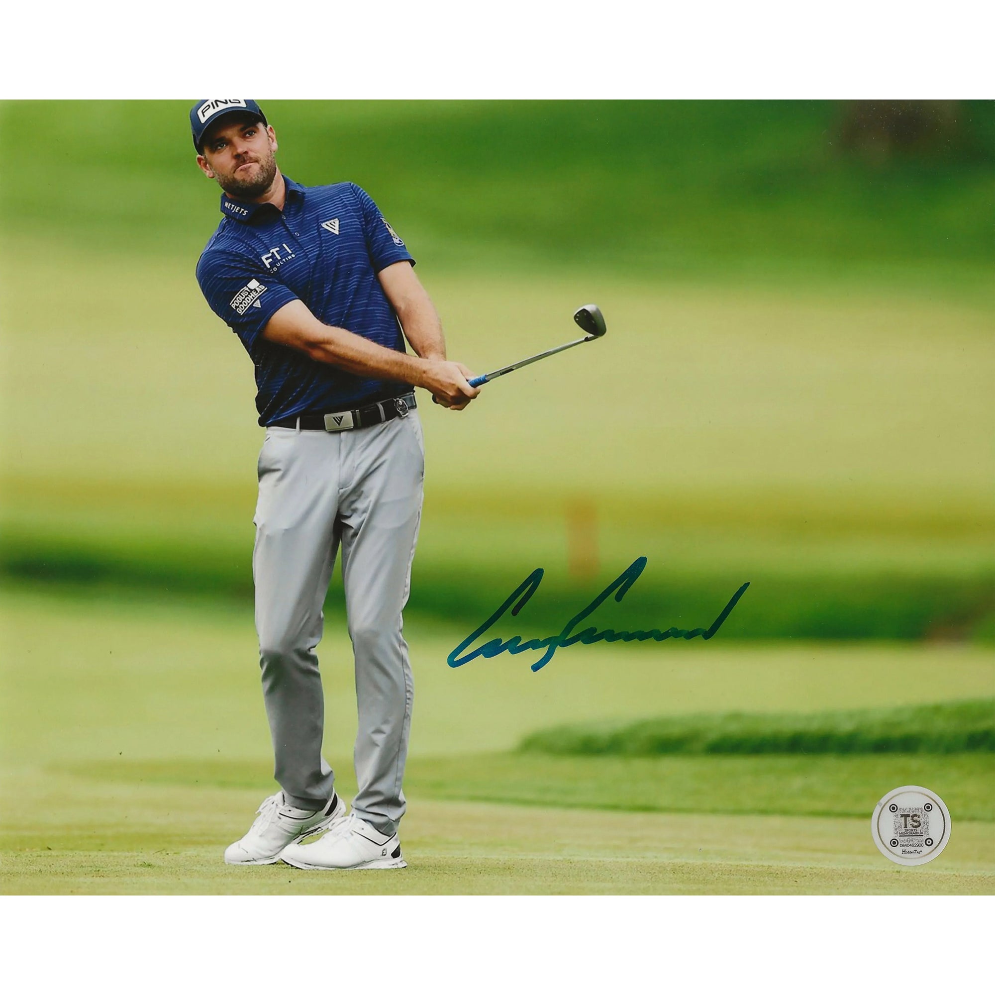 Golfer in blue shirt and gray pants swinging club on green golf course, autograph visible