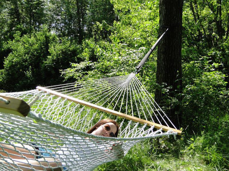 Woman relaxing in a cotton rope hammock outdoors among green trees