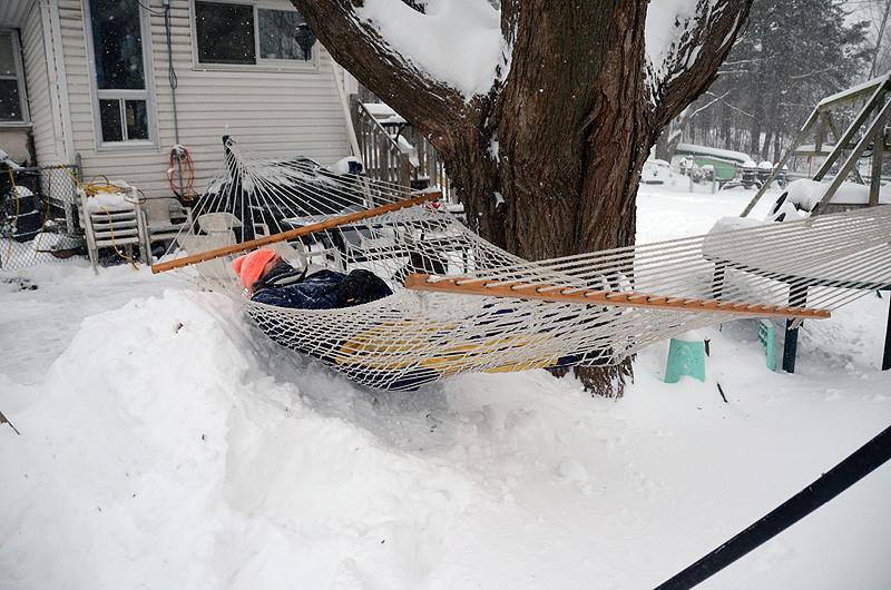Cotton rope hammock double hanging between tree and house in snowy backyard