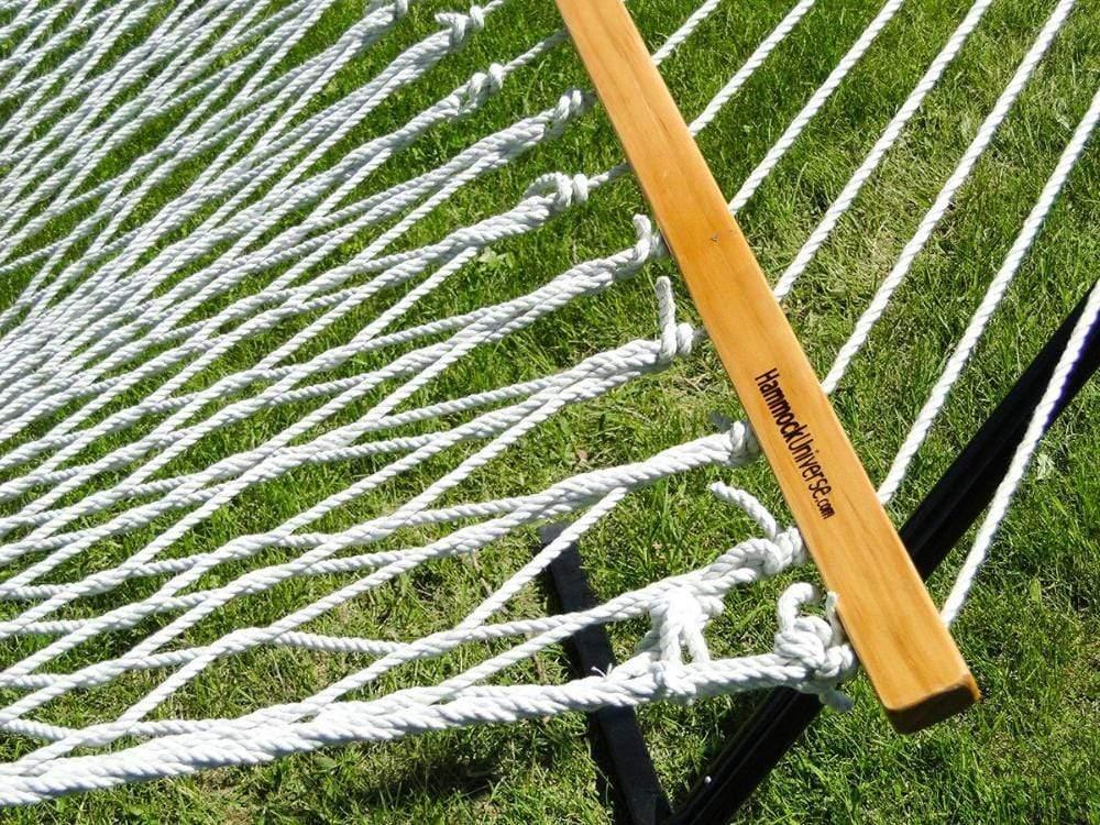 Cotton rope hammock with wooden spreader bar on a lawn, Hammock Universe branding visible.