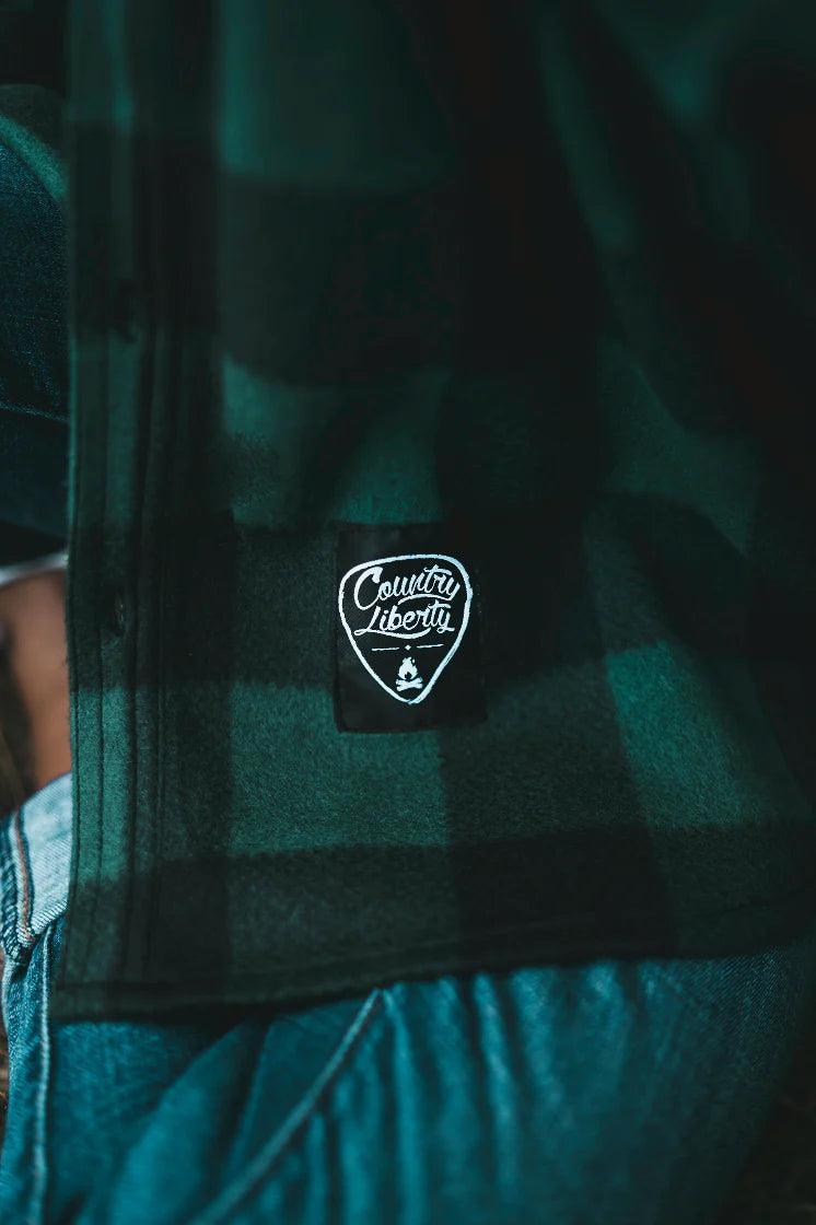 Country Liberty black and green plaid fleece jacket patch close-up, jeans visible
