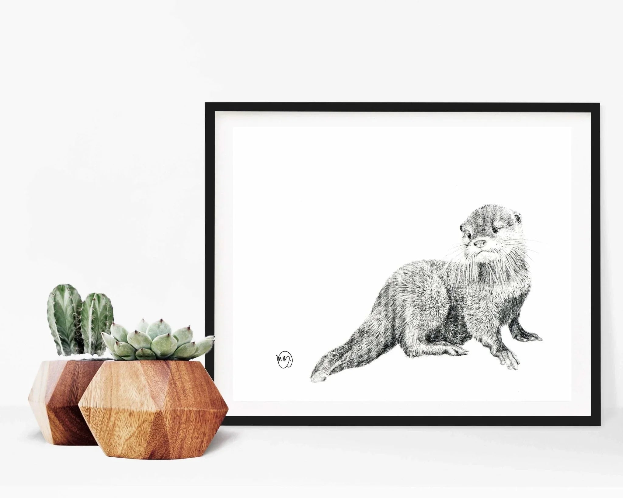 Framed baby otter sketch with geometric wooden plant pots and succulents on a white background