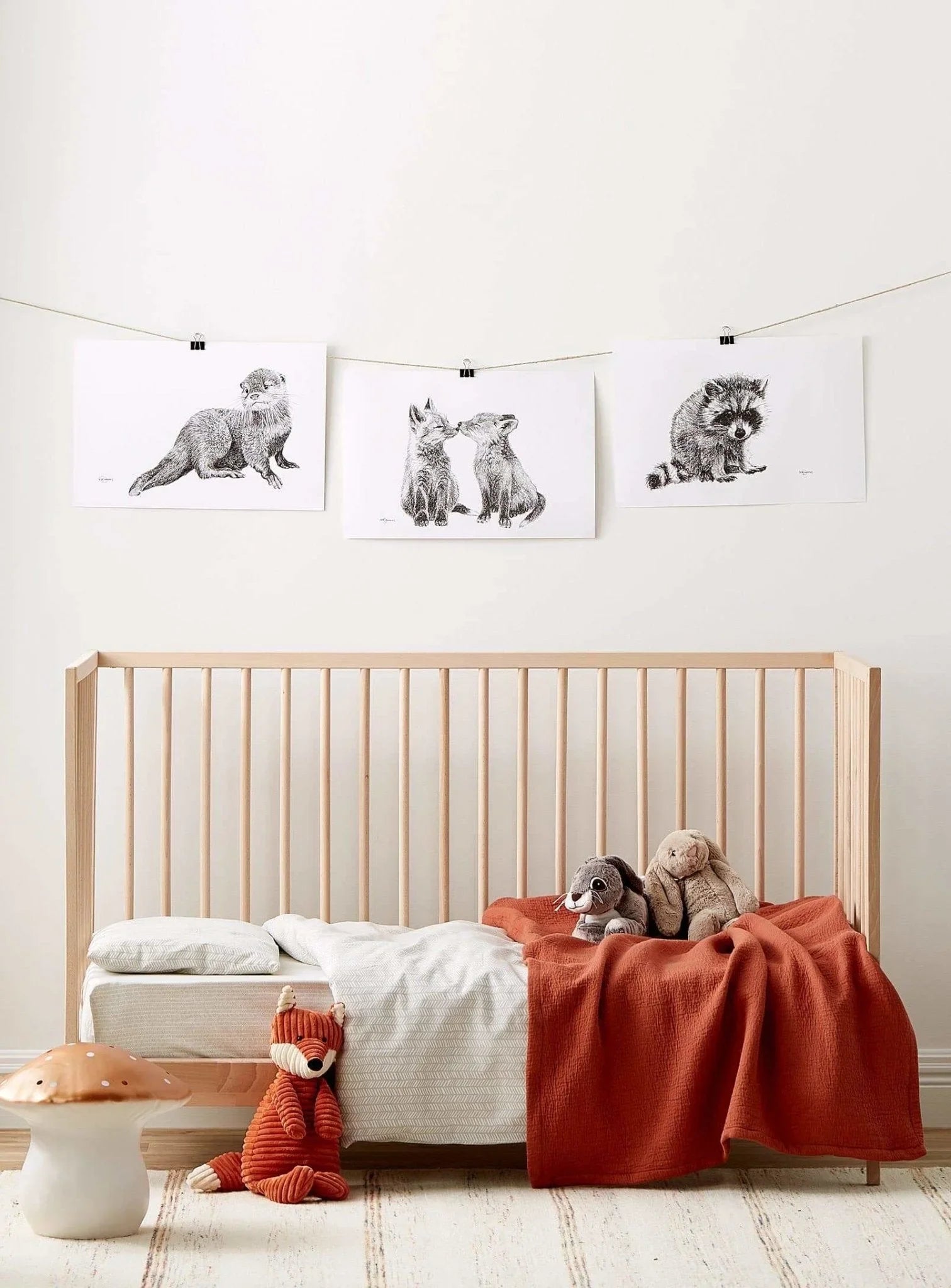 Cute baby otter art print hanging above a modern crib in a cozy nursery