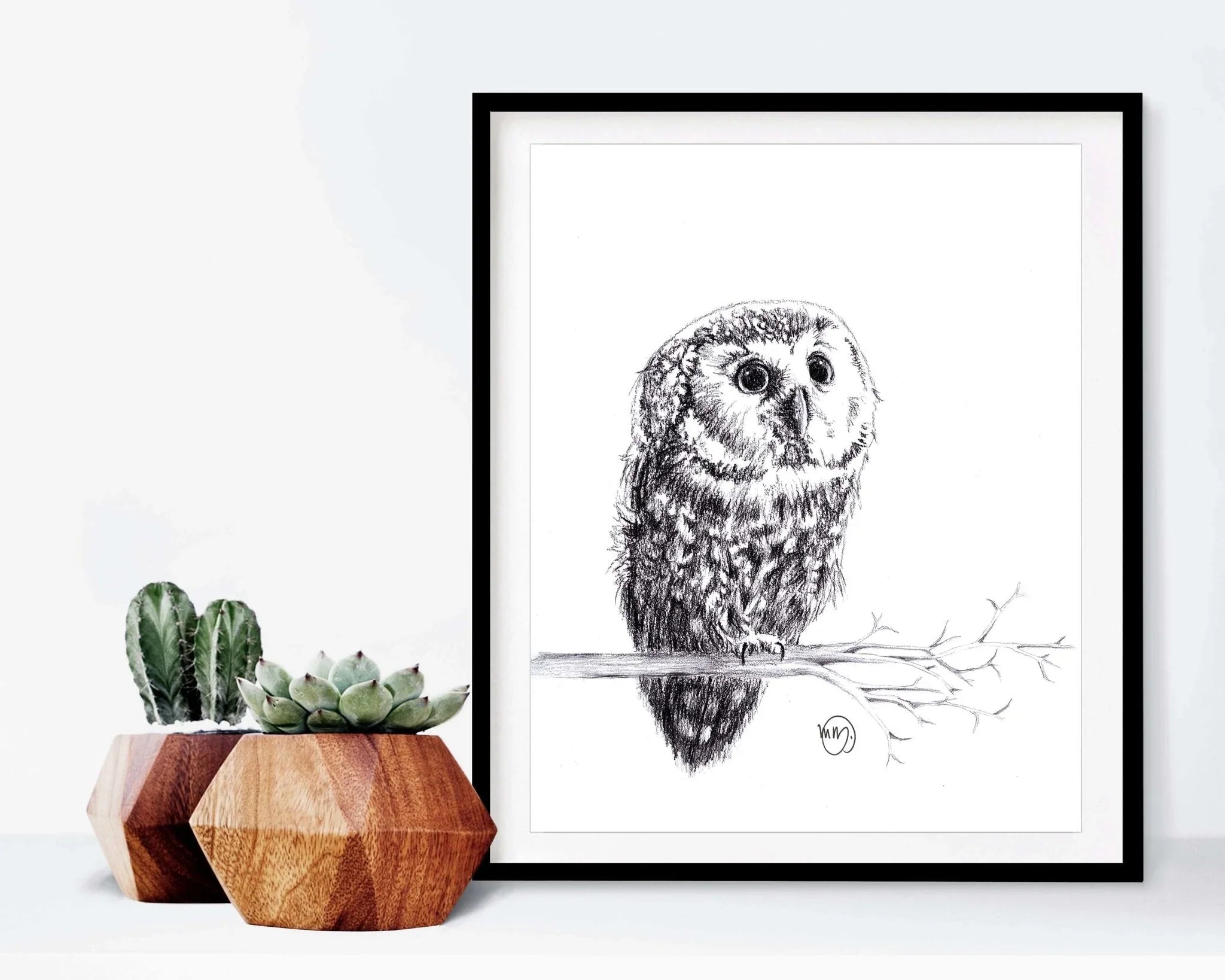 Framed pencil sketch of a baby owl on branch, next to geometric wooden succulent pots