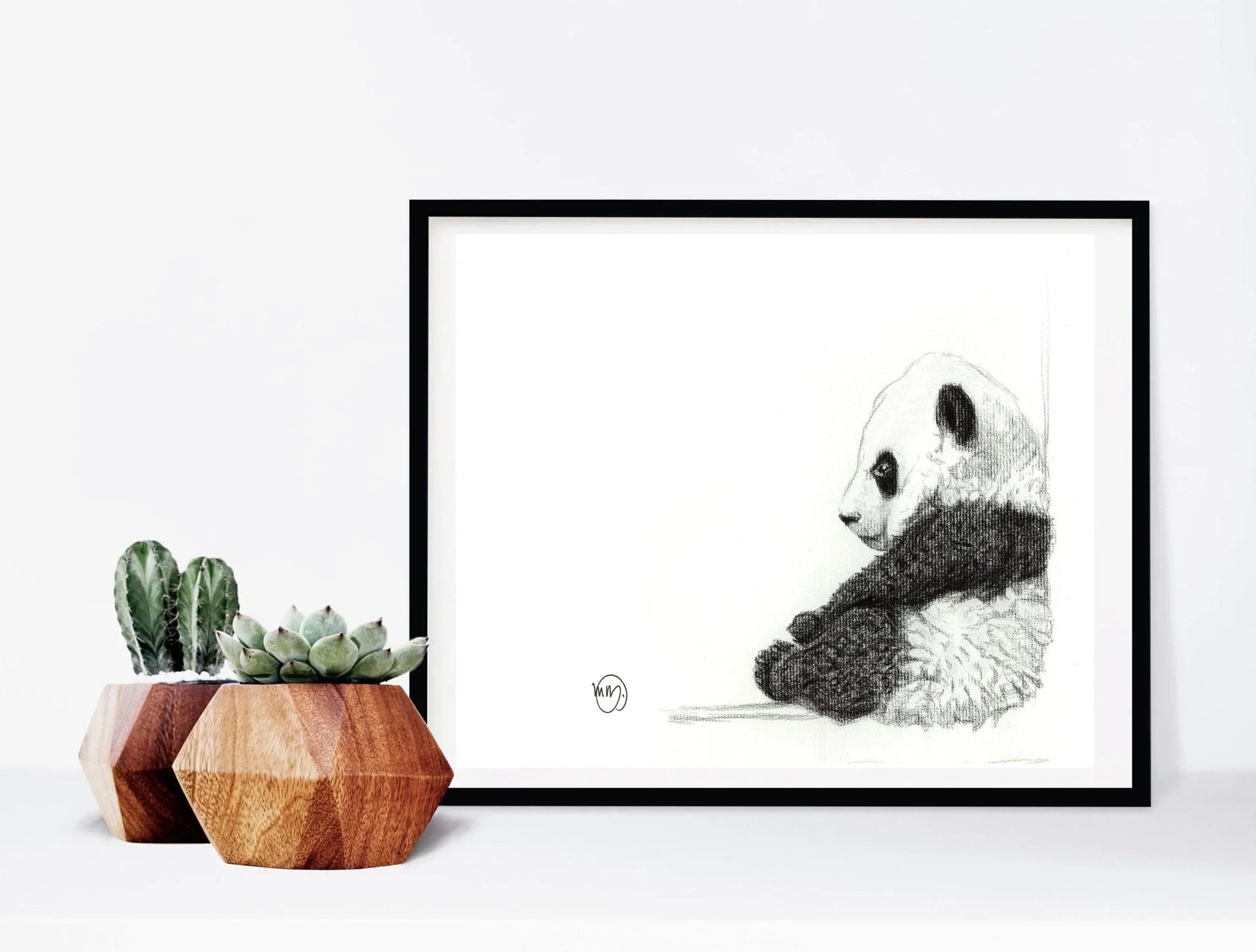 Framed pencil sketch of a sitting panda with potted succulents on a white desk