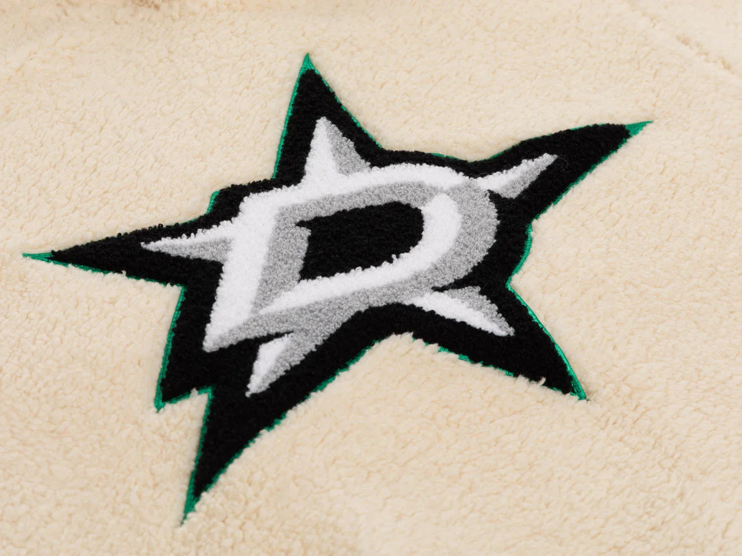 Black and gray star logo embroidered on beige sherpa fleece fabric