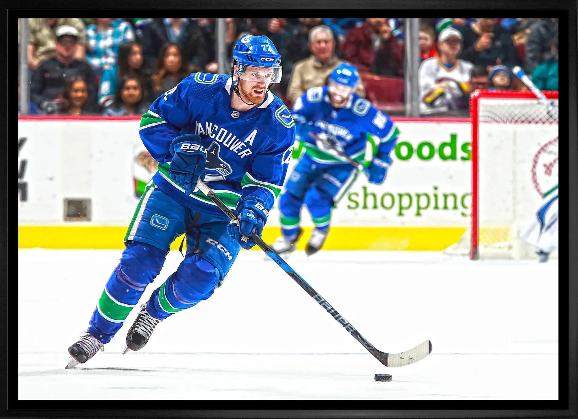 Vancouver Canucks hockey player in blue jersey skating with puck on ice during game