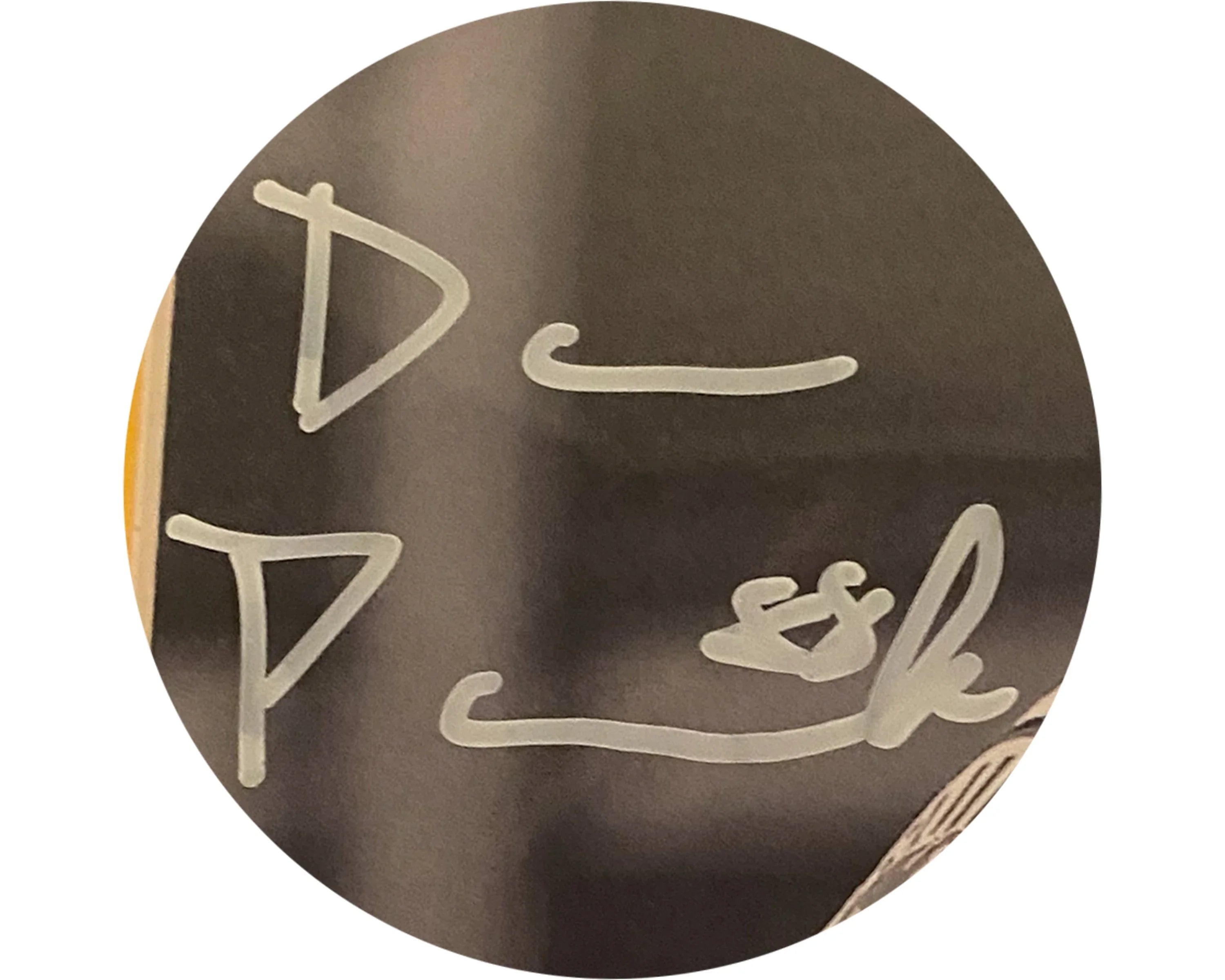 Close-up of handwritten white marker signature on dark circular background