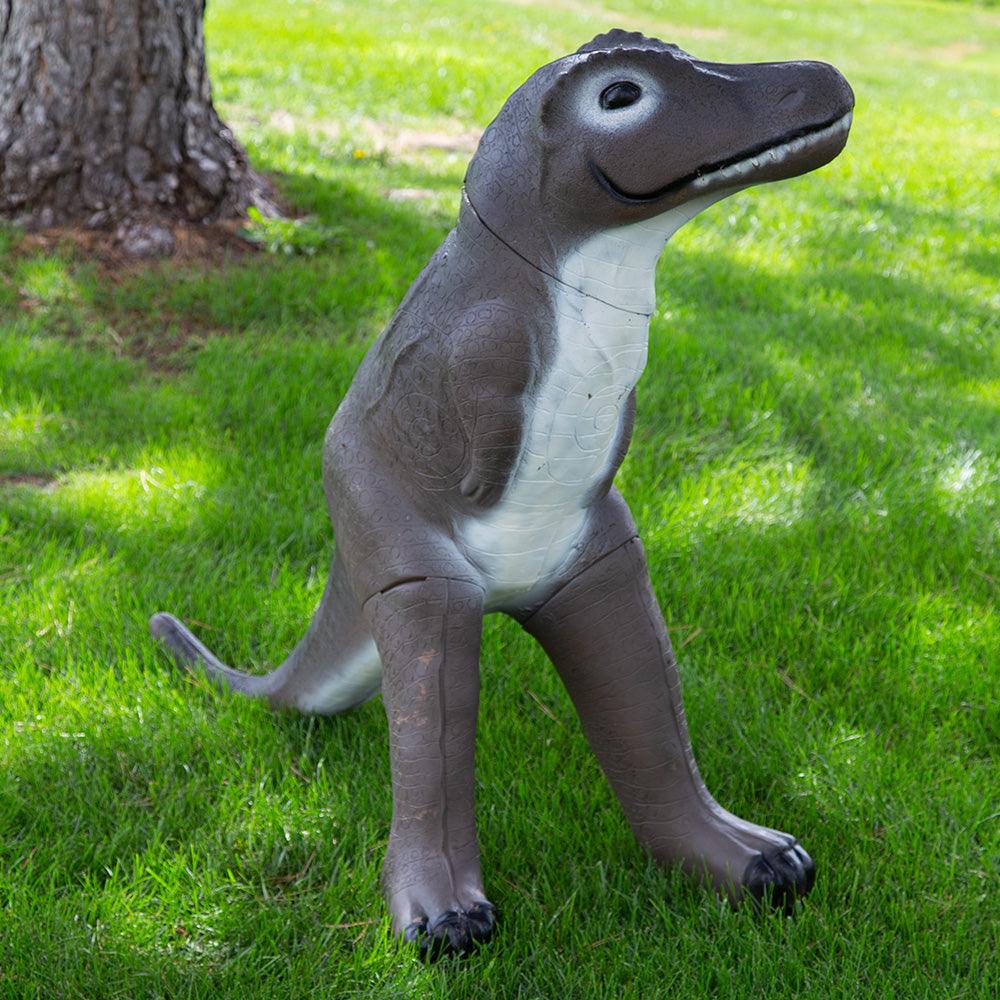 Realistic brown dinosaur statue on green grass lawn near a tree outdoors