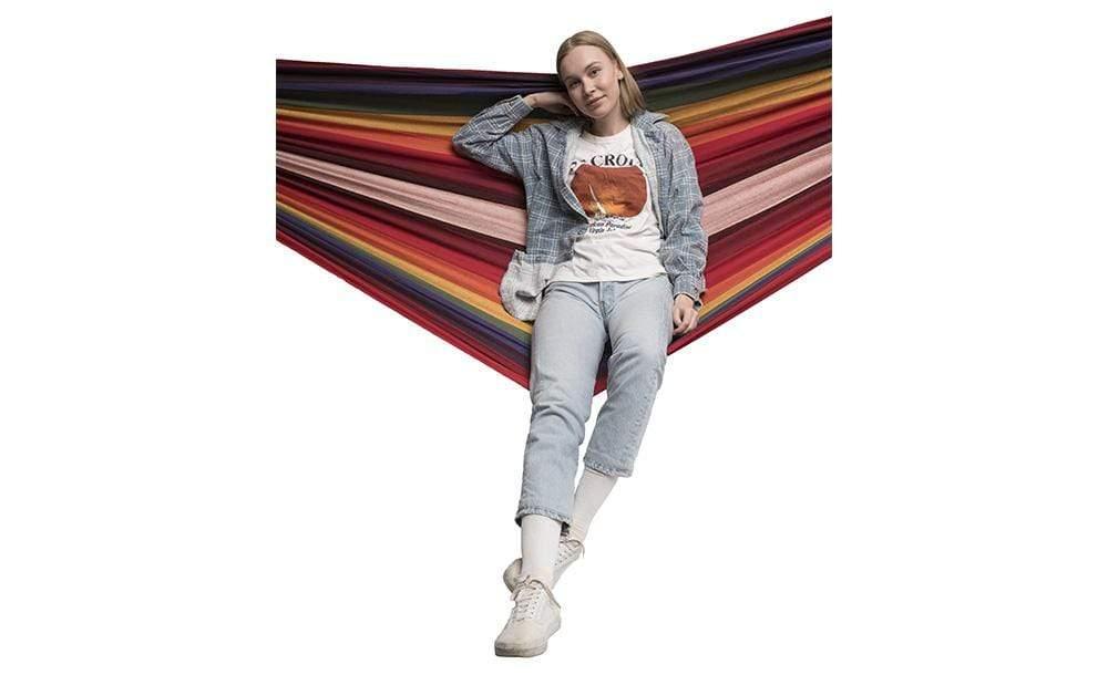 Woman sitting on a double Brazilian multicolor hammock against white background