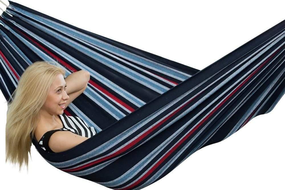 Woman relaxing in a striped Brazilian double hammock, navy blue with red and grey accents