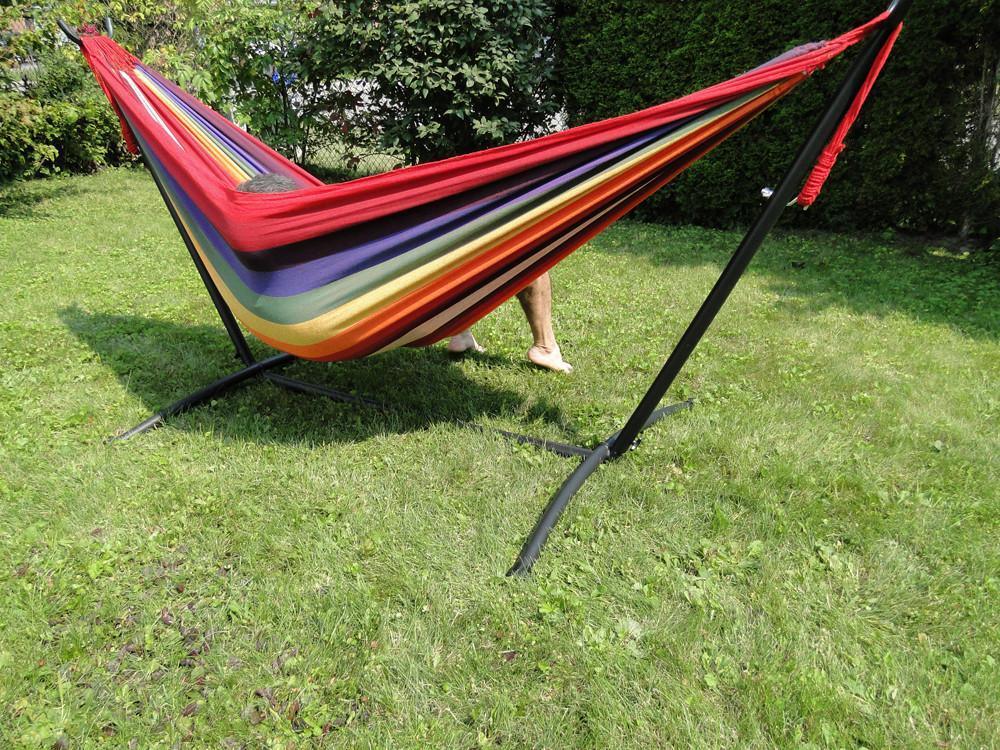 Colorful Brazilian double hammock on black stand in a grassy backyard