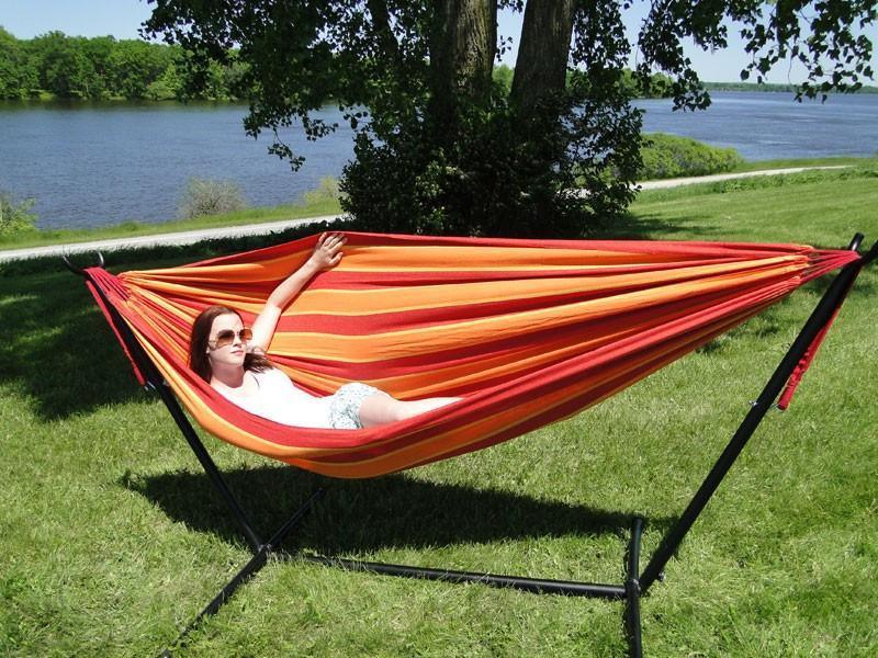 Woman lounging in red striped Brazilian style double hammock with universal stand outdoors