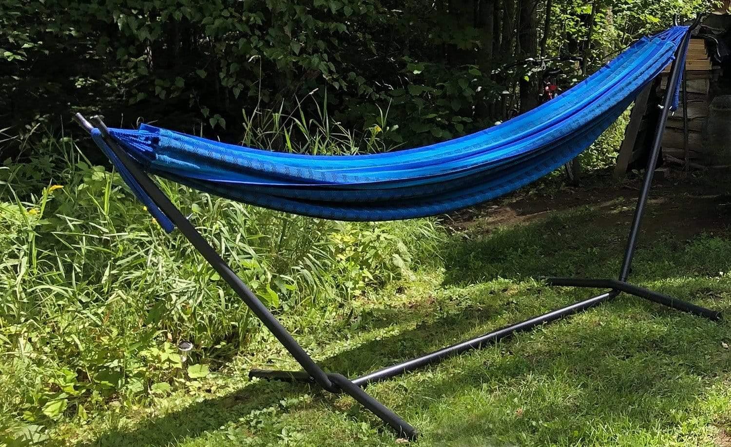 Blue and black striped Brazilian hammock on metal stand in a grassy outdoor garden