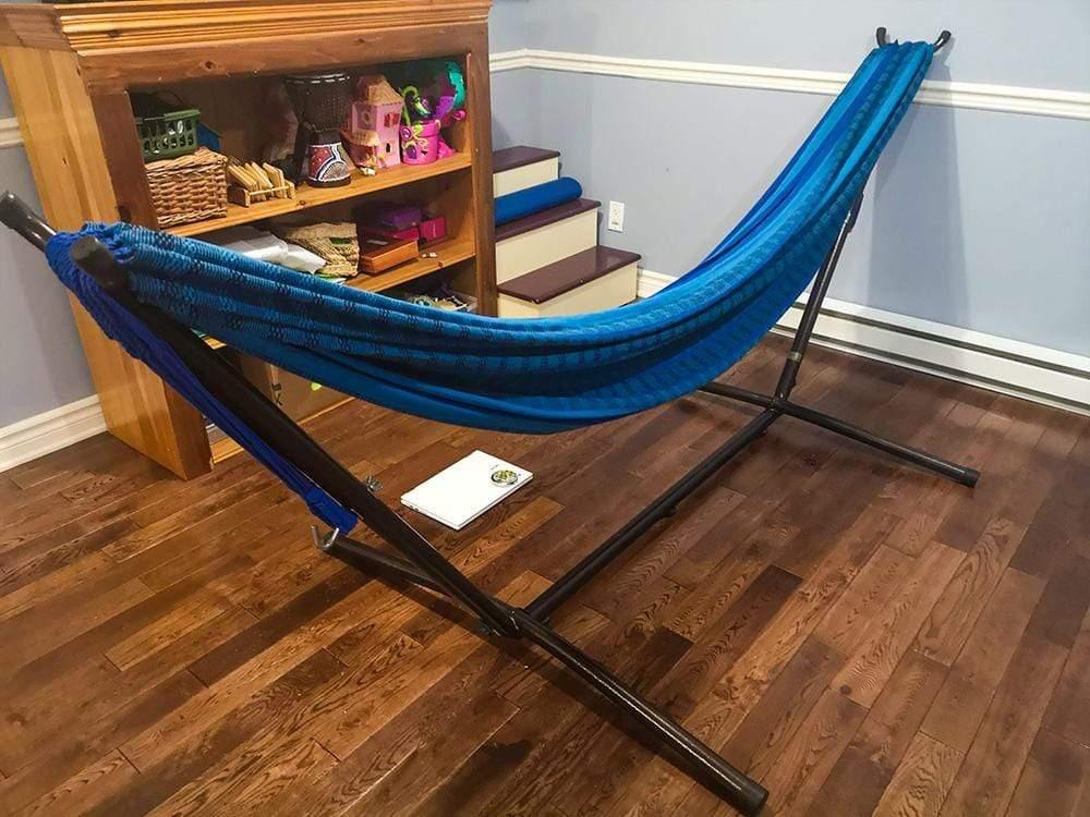 Blue and black Brazilian hammock on stand in cozy indoor wooden floor room