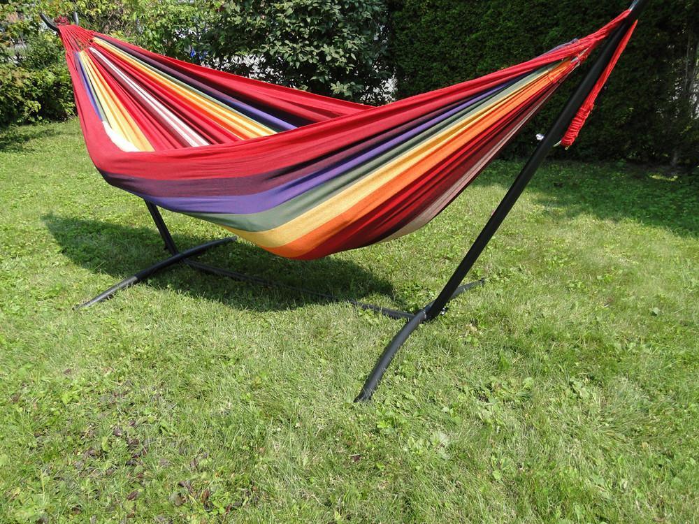Brazilian double hammock with vibrant rainbow stripes on a black metal stand outdoors