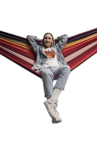 Woman relaxing in a multicolored double Brazilian hammock against a white background