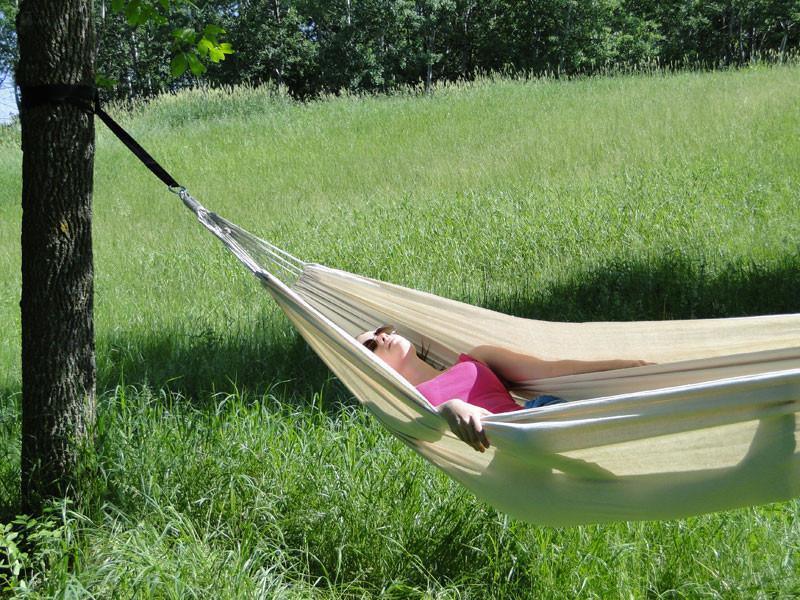 Woman relaxing in a Brazilian style hammock outdoors on green grass field