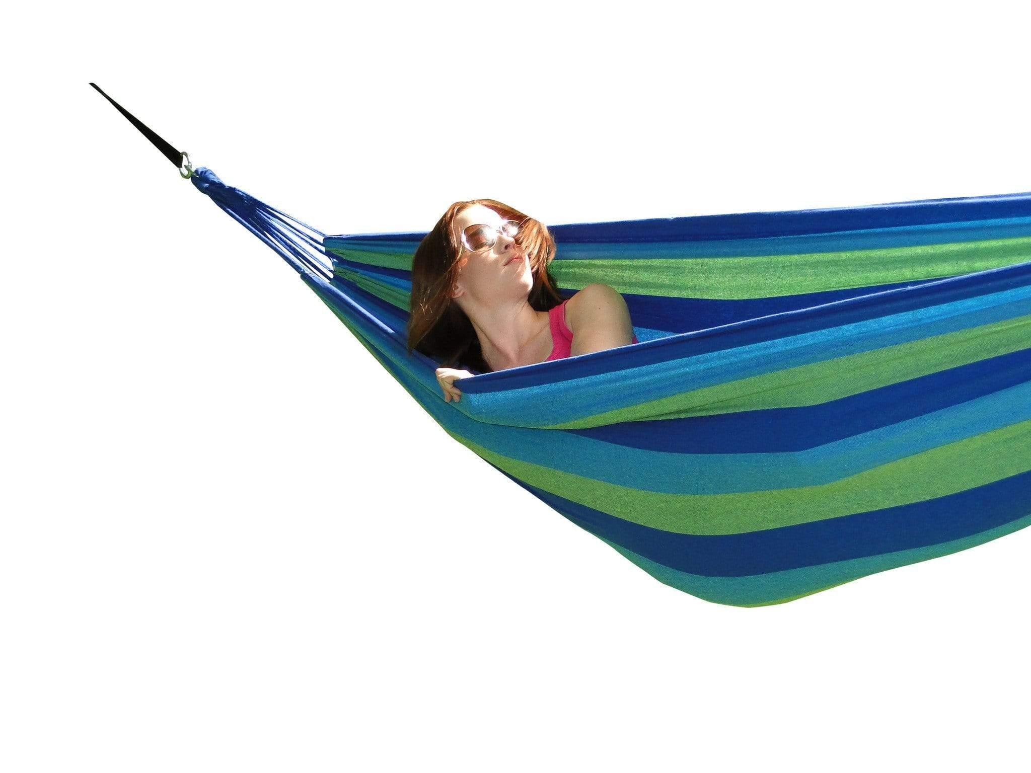 Woman relaxing in blue and green striped hammock on white background