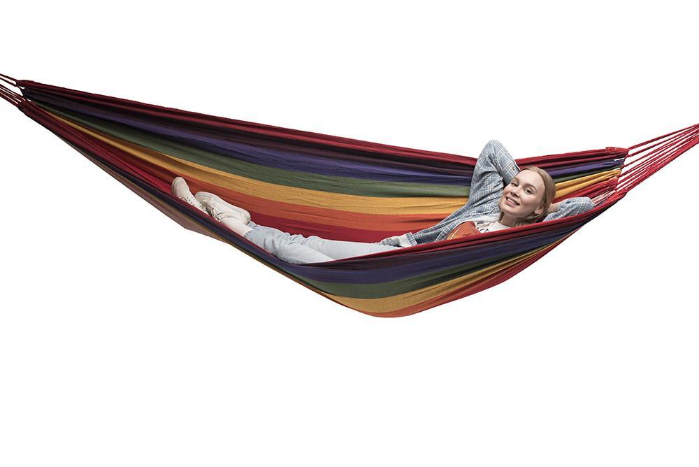 Woman relaxing in a multicolored double Brazilian hammock on a white background