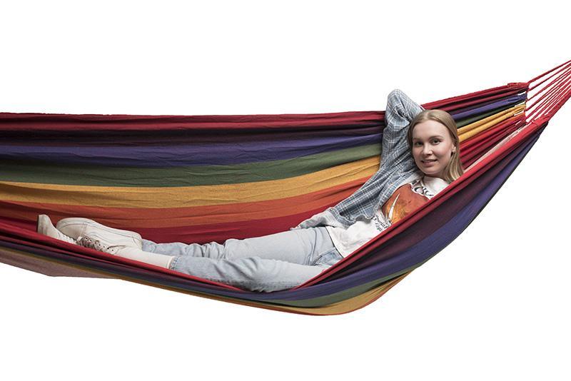 Woman relaxing in a multicolored Brazilian double hammock against white background