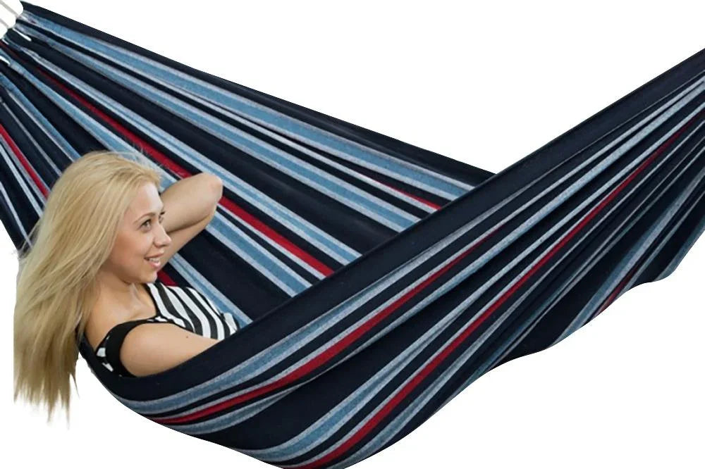 Woman relaxing in a blue striped Brazilian double hammock indoors